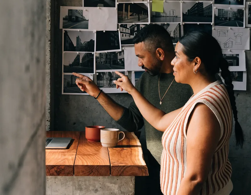 Dos personas del equipo creativo señalando un muro de referencias fotográficas
