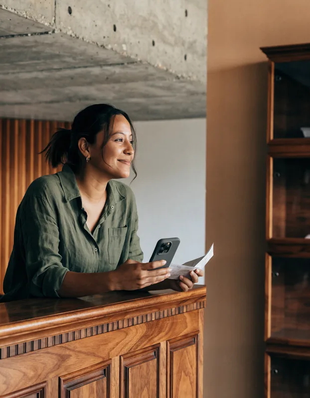 Daniela, administradora de ventas, con su celular y un recibo en el mostrador